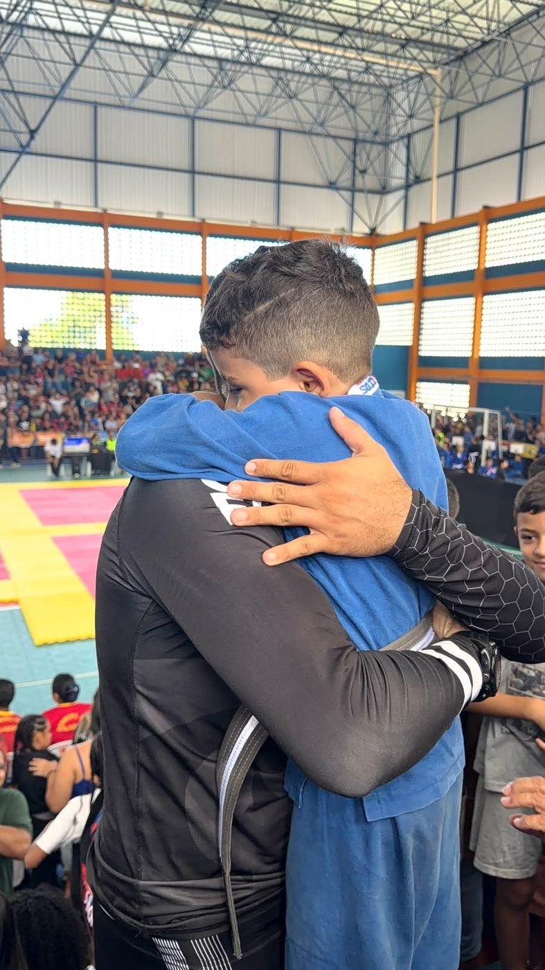 Professor Matheus Coimbra abraça um aluno criança depois da luta em campeonato