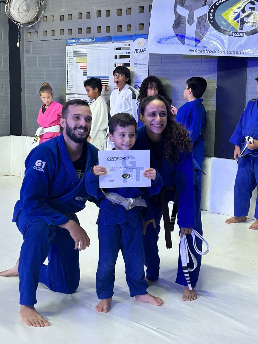 Aluno criança recebe o certificado de graduação ao lado dos professores